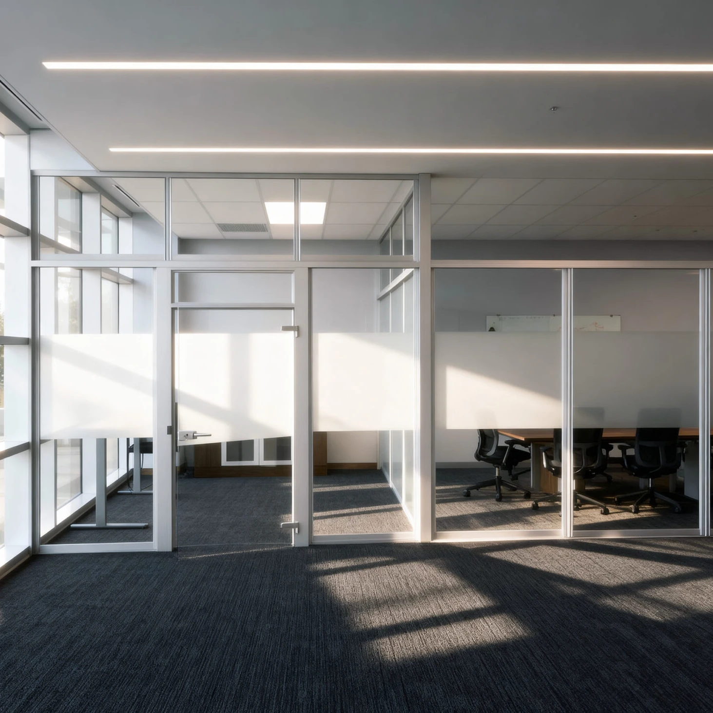 Komandor Aurora aluminum office glazing system designed with floor-to-ceiling glass partitions and integrated swing doors. The structure uses a silver aluminum framework with upper transom panels and a wide central frosted glass band for visual privacy. This architectural solution divides open spaces into acoustic meeting rooms while maintaining light transmission through tempered safety glass.