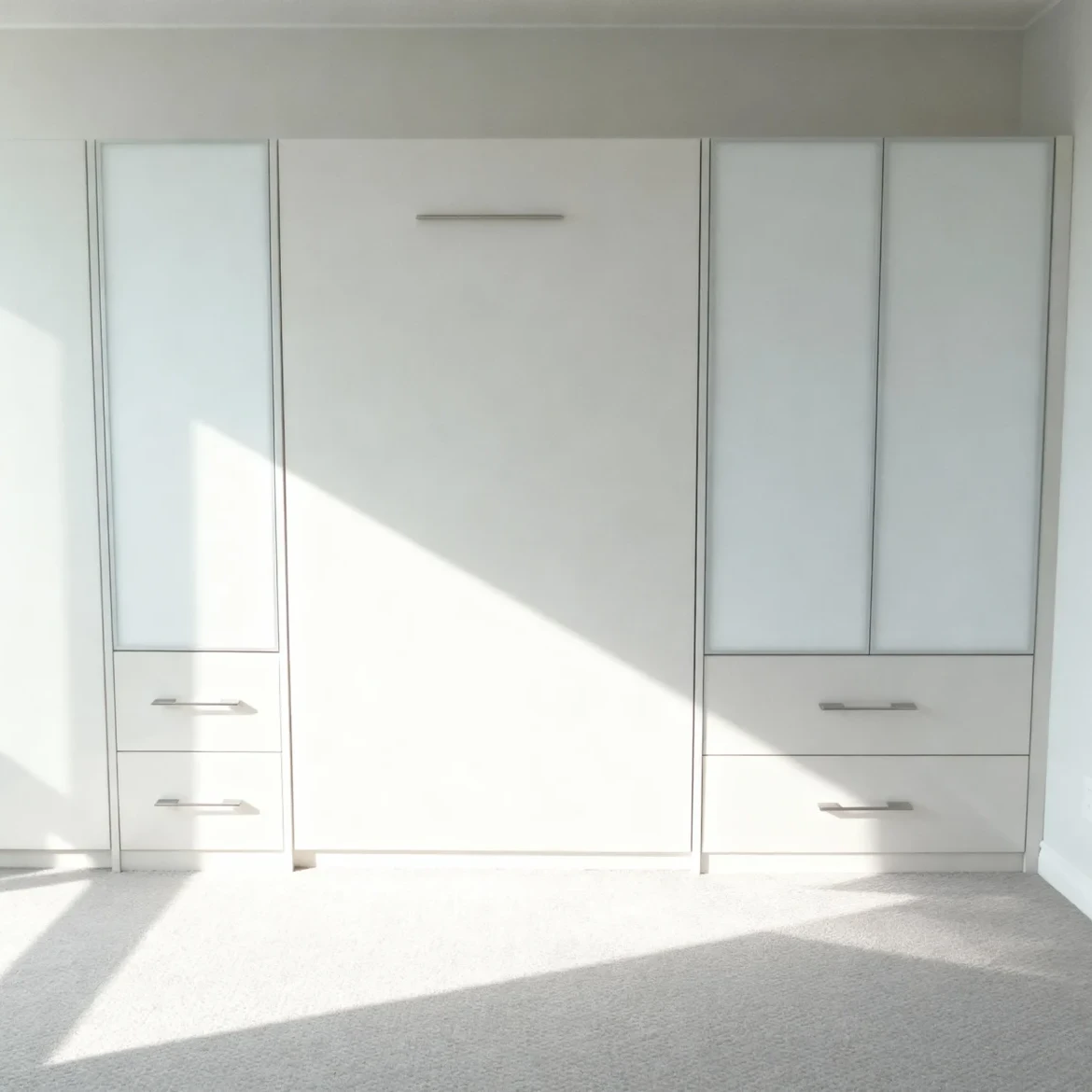 Komandor Murphy bed and space-saving furniture system integrated into a custom residential shelving and wardrobe unit. This architectural storage solution features a fold-away bed mechanism flanked by custom-built cabinetry manufactured to the nearest 1/32-inch using high-density European thermal-fused laminate. The system incorporates floor-to-ceiling shelving, soft-close drawer slides, and decorative hardware. Designed for modern GTA condo living, the millimeter-precise construction eliminates filler strips, providing a seamless hybrid of sleeping quarters and organized master suite storage.