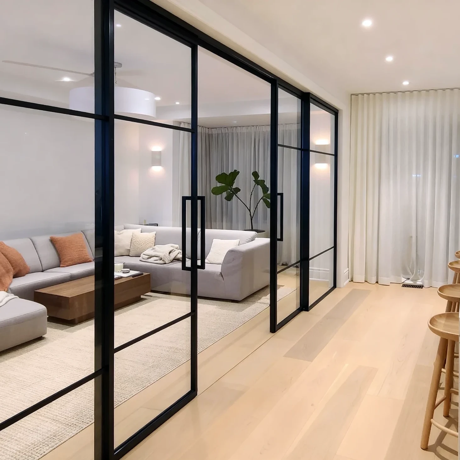 Komandor Lumi aluminum-framed interior glazing system and glass wall partition featuring a matte black finish. This high-end architectural partition utilizes an aluminum framed interior glazing system with a swing door and fixed panels. The Lumi system provides a stylish solution to divide open space while maintaining transparency. The structural framework is engineered with precision aluminum profiles that accept various insert materials, providing a modern, minimalist aesthetic for residential interiors and custom room divisions.