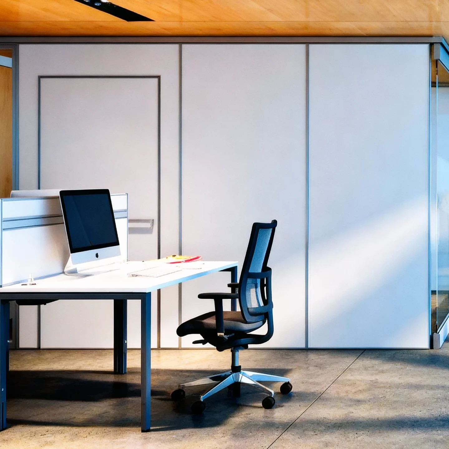 Komandor commercial modular partition wall system configured with floor-to-ceiling solid opaque white panels to define a private office workstation. The assembly features a robust aluminum structural framework that integrates a flush-mounted swing door for access. [cite_start]This custom solution allows for the rapid creation of subdivided office spaces and corridors without the mess and permanency of traditional drywall and framing[cite: 28, 30].