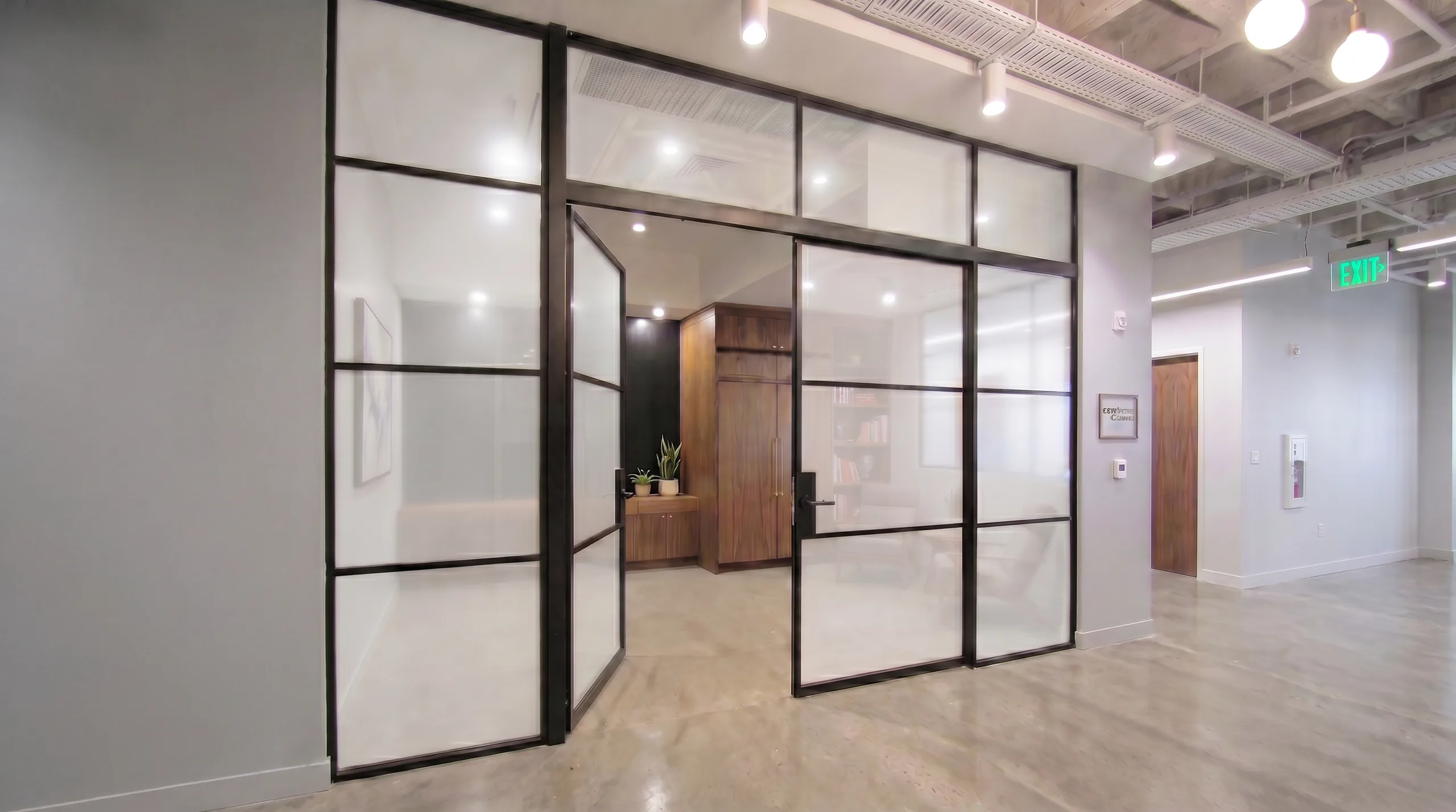 Black aluminum grid-framed glass office partition with frosted lower panels and a swing glass door by Komandor
