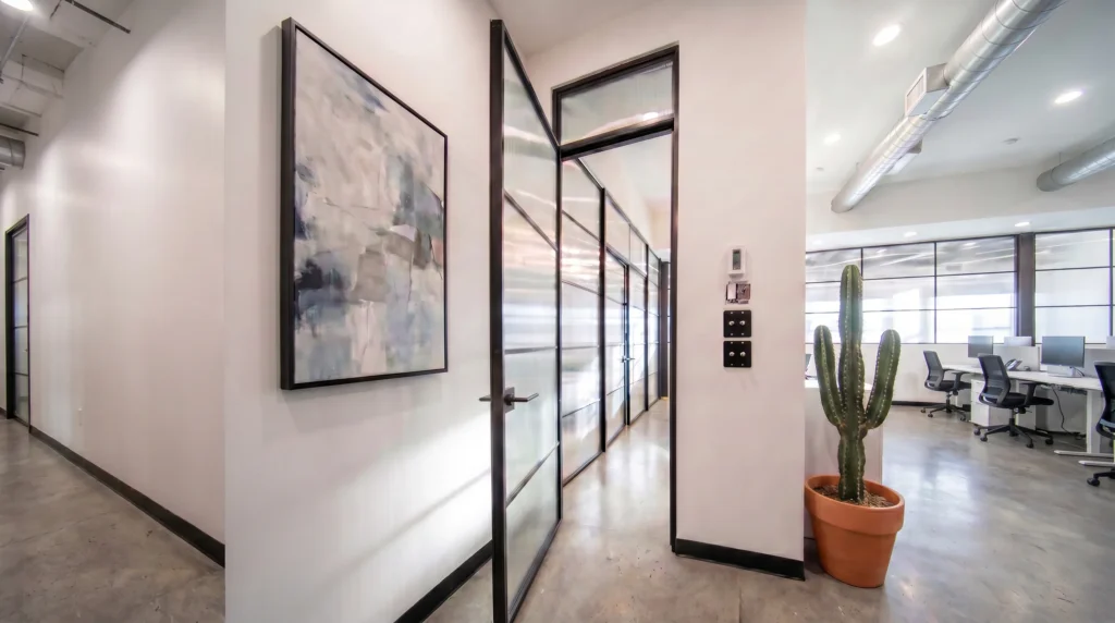 Fluted glass office partition set in slim black aluminum frames lining a corridor by Komandor